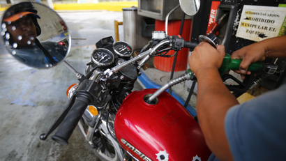 A man pumps gasoline at a service station in Caracas August 7, 2014. Venezuela will raise gasoline prices, the country's oil minister told reporters on Tuesday, repeating a government promise to increase the world's lowest fuel prices for the first time in two decades. Oil Minister Rafael Ramirez did not give a timeline for the increase, but said it would not be comparable to international prices. According to government figures, cheap fuel costs the gasoline subsidiary of state-run oil company PDVSA $12.5 billion in losses annually. REUTERS/Jorge Silva (VENEZUELA - Tags: ENERGY POLITICS)