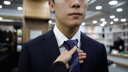 man in suit tries on tie