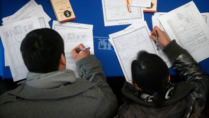 Job seekers fill in application forms during a job fair at Shanghai Stadium