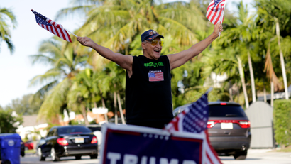 Peter Knapp, a supporter of Republican candidate Donald Trump, waves American flags as he stands outside his home on Election Day, Tuesday, Nov. 8, 2016, in Miami.