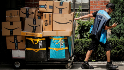 An Amazon delivery worker pulls a delivery cart full of packages during its annual Prime Day promotion in New York City