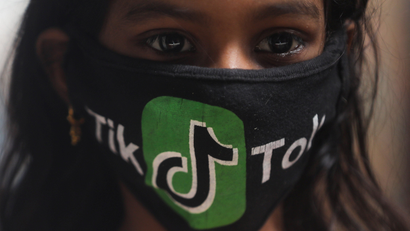 A girl wearing a protective mask depicting the TikTok logo poses for a picture inside a slum in Mumbai
