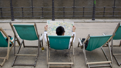 Tourist reads Berlin city map as he sits in deck chair at river Spree embankment in Berlin