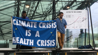 Two members of the "Doctors for Extinction Rebellion" group hold up a sign that reads "climate crisis is a health crisis."