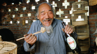 Man eating with chopsticks and drinking beer.