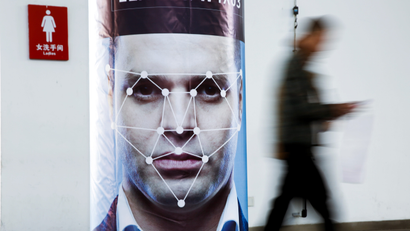 A man walks past a poster simulating facial recognition software