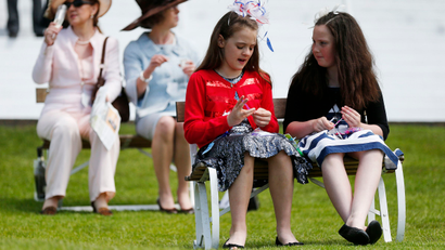 Girls make bracelets while they wait for the start of the first race in the Royal Enclosure at the Epsom Derby Festival in Epsom, southern England June 7, 2014.