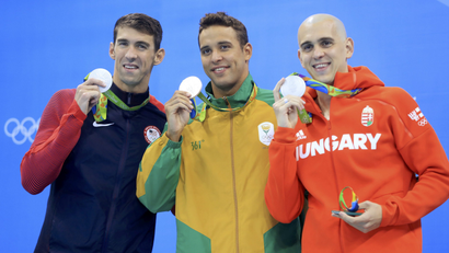 Swimmers Michael Phelps, Chad le Clos, and Laszlo Cseh hold up their silver medals in a three-way tie at the Olympics.