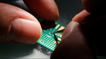A researcher plants a semiconductor on an interface board during a research work to design and develop a semiconductor product at Tsinghua Unigroup research centre in Beijing, China