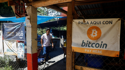 A banner hanging on the exterior wall of a restaurant in El Salvador reads "Pay here with Bitcoin."