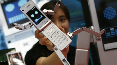 A woman poses with the SoftBank Mobile Corp's robot-shaped mobile phone "Phone Braver 815T PB" at the International Tokyo Toy Show in Tokyo