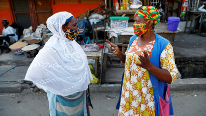 Two women, in multicolored face masks, speak