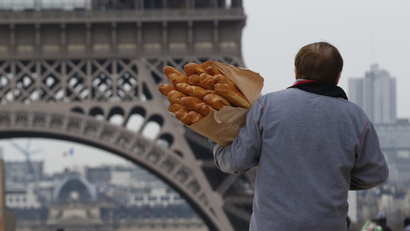 A man carries loaves of French bread.