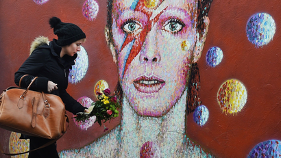 A women lays flowers at a mural of British singer David Bowie in Brixton, birth place of the late David Bowie in London, Britain, 11 January 2016.