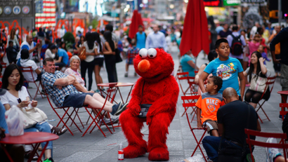 Jorge, an immigrant from Mexico, dressed as the Sesame Street character Elmo rests in Times Square, New York