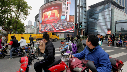 People watch a broadcast of Chinese President Xi Jinping delivering his speech during the opening of the 19th National Congress of the Communist Party of China, on a giant outdoor screen in Nanjing, Jiangsu province, China October 18, 2017. REUTERS/Stringer ATTENTION EDITORS - THIS IMAGE WAS PROVIDED BY A THIRD PARTY. CHINA OUT. - RC15E60F6D70