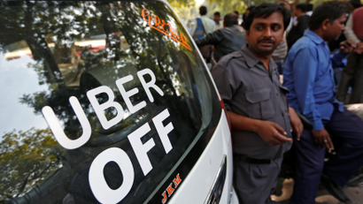 Uber and Ola drivers stand next to their parked vehicle's during a protest in New Delhi