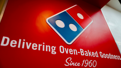A sign at a Domino's Pizza that reads "Delivering oven-naked goodness since 1960" with the Domino's domino-piece logo.