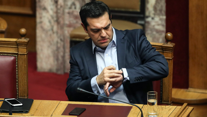 Greece's Prime Minister Alexis Tsipras checks his watch during a parliamentary session in Athens, Saturday, Dec. 10, 2016. Greek parliament votes on 2017 budget, as the country's left-wing government is still negotiating a new series of cost-cutting reforms that are expected to remove protection measures for private sector jobs and distressed mortgage holders. (AP Photo/Yorgos Karahalis)