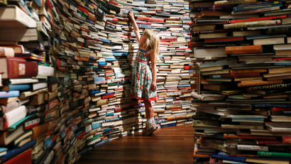 Leona, 7, poses inside a labyrinth installation made up of 250,000 books.
