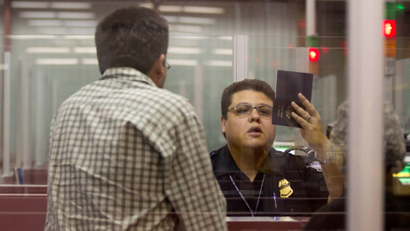 A Customs and Border Protection officer checks the passport of a non-resident visitor to the United States inside immigration control at McCarran International Airport