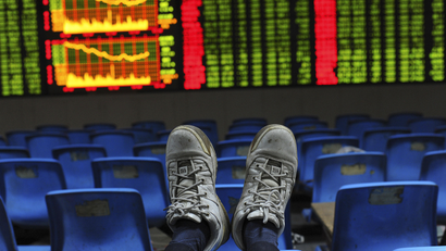 An investor puts his feet onto the back of a chair in front of an electronic board displaying stock information at a brokerage house in Hefei, Anhui province October 26, 2012.