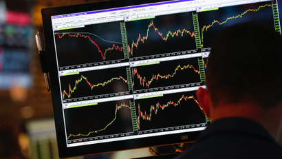 A screen displays stock charts while a trader works at his post on the floor at the New York Stock Exchange, May 30, 2013.