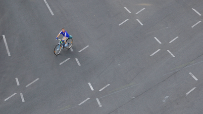 A man on a bicycle drives over an empty street in front of victory column 'Siegessaeule' in Berlin