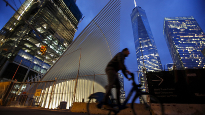 A man cycles past the Oculus structure of the World Trade Center Transportation Hub and the One World Trade Center building in New York