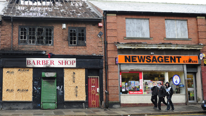 Three youths walk past boarded-up shops in Newcastle