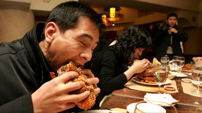 A Chinese man and a woman eat hamburger during a Burger King contest in XiAn, northwest Chinas Shaanxi province, January 22, 2007. Obesity levels in China are rising fast, with more than a quarter of the adult population overweight or obese, as people add more meat and dairy products to their diet, causing serious health problems, a new study says. Chinese people now derive a far larger proportion of energy from fat and animal-based foods, such as meat and eggs, compared with in the past, the study found. The change in diets and lifestyles, where Chinese less frequently have to engage in physical activity at work, is consequently leading to a rise in cancer and coronary heart disease. According to the study, the classical Chinese diet -- rich in vegetables and carbohydrates with minimal animal-sourced food -- no longer exists.(Imaginechina via AP Images