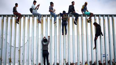 Members of a caravan of migrants from Central America climb up the border fence between Mexico and the U.S., as a part of a demonstration prior to preparations for an asylum request in the US