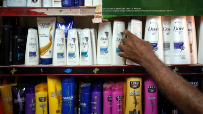 A salesman takes a bottle of Hindustan Unilever Limited (HUL) Dove shampoo from a shelf at a shop in Mumbai April 30, 2013. Unilever plans to pay up to $5.4 billion to raise its stake in its Indian subsidiary, making its biggest deal in 13 years a huge bet on the strength of demand for personal care and food products in Asia's third-largest economy.