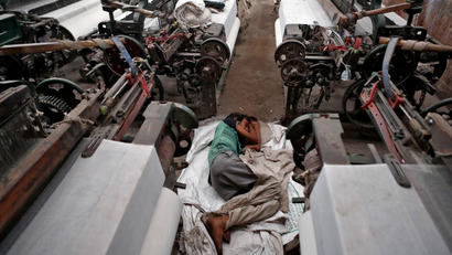 A young worker sleeps between looms in a factory in India