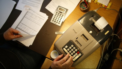 A German banker works with an old adding machine.
