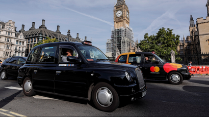 Black taxis pass the Houses of Parliament in London