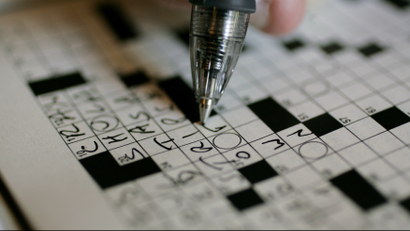 A pen touching a crossword puzzle