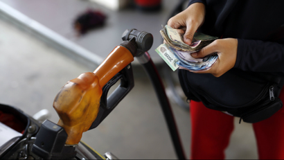 A worker at a state-owned Pertamina petrol station holds money as a motorcycle is filled with subsidised fuel in Jakarta, Indonesia.