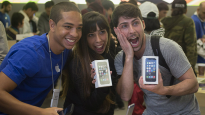 Customers pose with their new Apple iPhone 5s phones with an Apple employee at the Apple Retail Store on Fifth Avenue in Manhattan, New York.