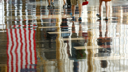A U.S. flag is reflected on the floor as passengers make their way through Reagan National Airport in Washington, U.S., July 1, 2016