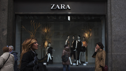 People walk by one of Zara's stores in central Madrid December 14, 2011. Sales growth at Spain's Inditex, the world's largest clothing retailer and owner of the popular Zara label, eased in the third quarter as the euro zone debt crisis rattled shoppers and unseasonably good autumn weather altered spending patterns. But the company, founded by Spain's richest man Amancio Ortega, still cheered the market with evidence it remains capable of outperforming rivals. The group reported a surprise 100 basis point increase in its profit margin and said sales growth in the fourth quarter had recovered.