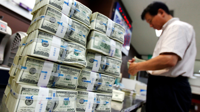 An employee of the Korea Exchange Bank counts money next to stacks of one hundred U.S. dollar banknotes at the bank's headquarters in Seoul, August 11, 2011. U.S. stock futures rose 1.5 percent on Thursday after a sharp drop in the cash index overnight, limiting Asian share losses, though focus will shift quickly to how European markets hold up to a sovereign debt crisis that has spread to its banking system.