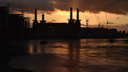 A rig surrounds one (2nd L) of the four chimneys of Battersea Power Station at sunset.