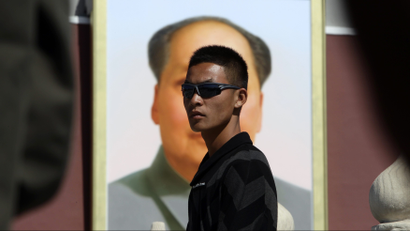 A plainclothes paramilitary policeman keeps watch in front of a portrait of China's late chairman Mao Zedong as tourists walk through Tiananmen Gate in Beijing October 1, 2011, on China's 62nd National Day.