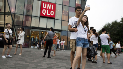 A Chinese couple take a selfie outside the Uniqlo flagship store where a steamy video purportedly taken inside one of its fitting room showing a couple apparently having sex in Beijing, Thursday, July 16, 2015. While online searches for the Japanese clothing brand soared after the viral spread of the video, it has also drawn the concern of the police and China's highest web regulator who are investigating whether it was a vulgar marketing gimmick.