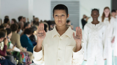 A model holds up their hands to reveal the words "Mental health is not fashion" on the Gucci runway