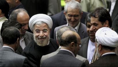 Iranian President Hasan Rouhani, center left with white turban, leaves at the conclusion of a session of the parliament to debate on his proposed Cabinet in Tehran, Iran, Tuesday, Aug. 13, 2013. In what is expected to be three days of debate ending Wednesday, legislators will vote individually to approve or reject each minister in Rouhani's 18-member Cabinet. (AP Photo/Ebrahim Noroozi)