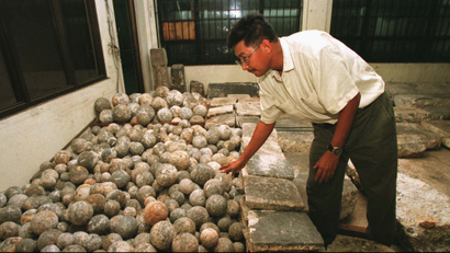 Filipino Archeologist Dr. Eduardo Dizon examines hundreds of rounded granite stones as he segregates them for proper identification along with other granite slabs inside the National Museum in Manila Monday, Aug. 4, 1997 following its discovery last May from an ancient shipwreck off the contested islands of Spratlys in the south China Sea. The 18th Century find, made up of granite slabs, tombstones, and ball-like "stone crushers" for mining, were believed to be part of artifacts being smuggled to Europe. (AP Photo/Bullit Marquez