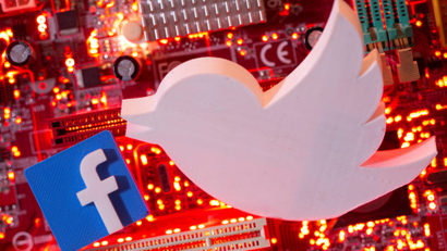 3D printed Facebook and Twitter logos are placed on a computer motherboard.