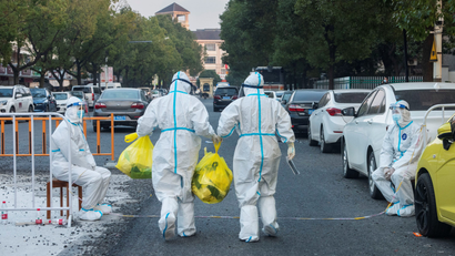 Two workers in hazmat suits walk in the city of Ningbo during a lockdown